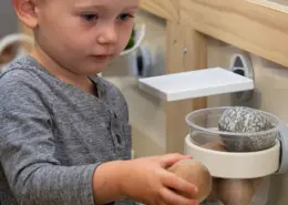 Park West (9)-web A child engaged in a practical life activity, carefully transferring water with a sponge.